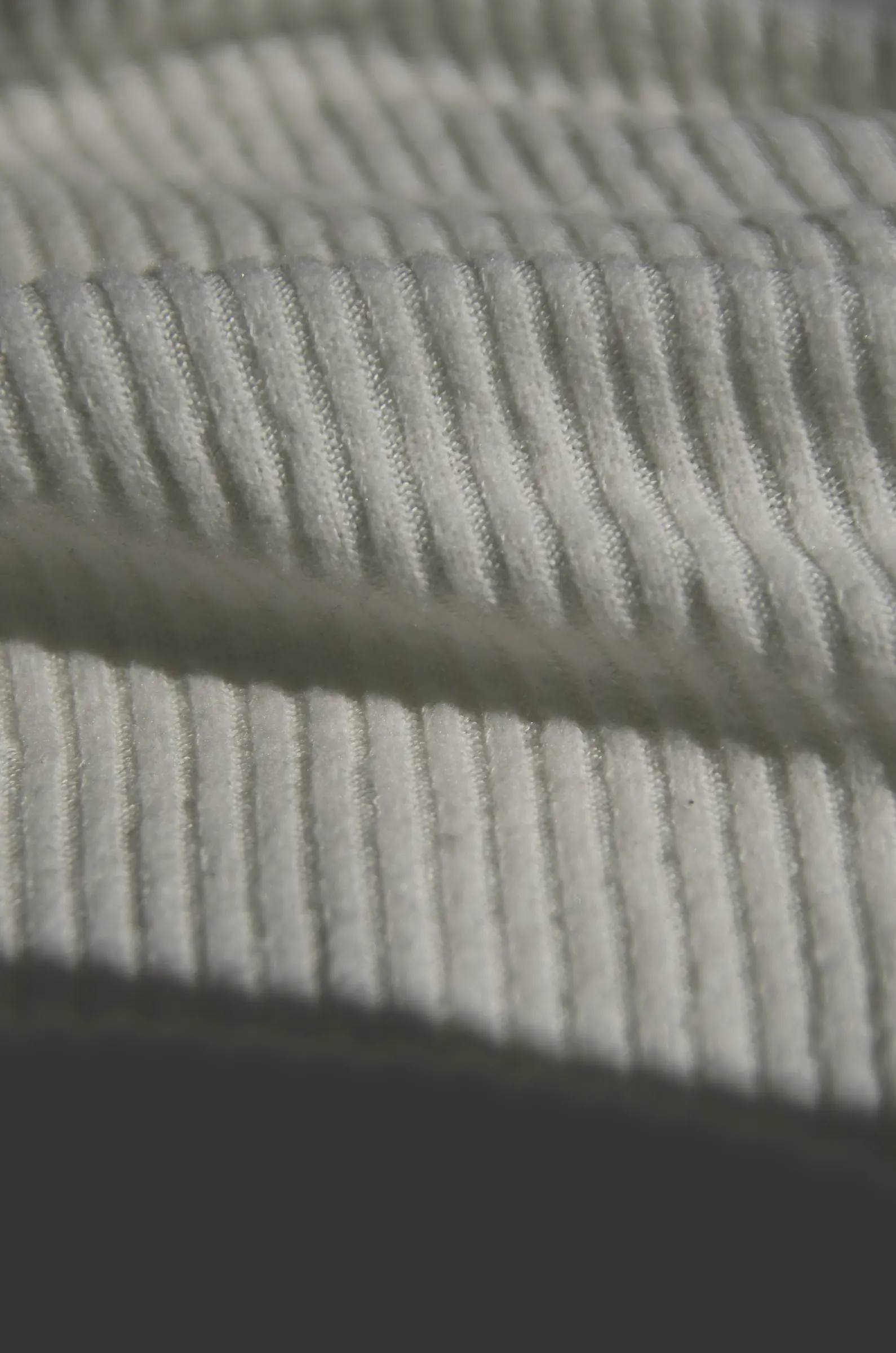 Close-up of pale grey rib-knit cuffs in raking light