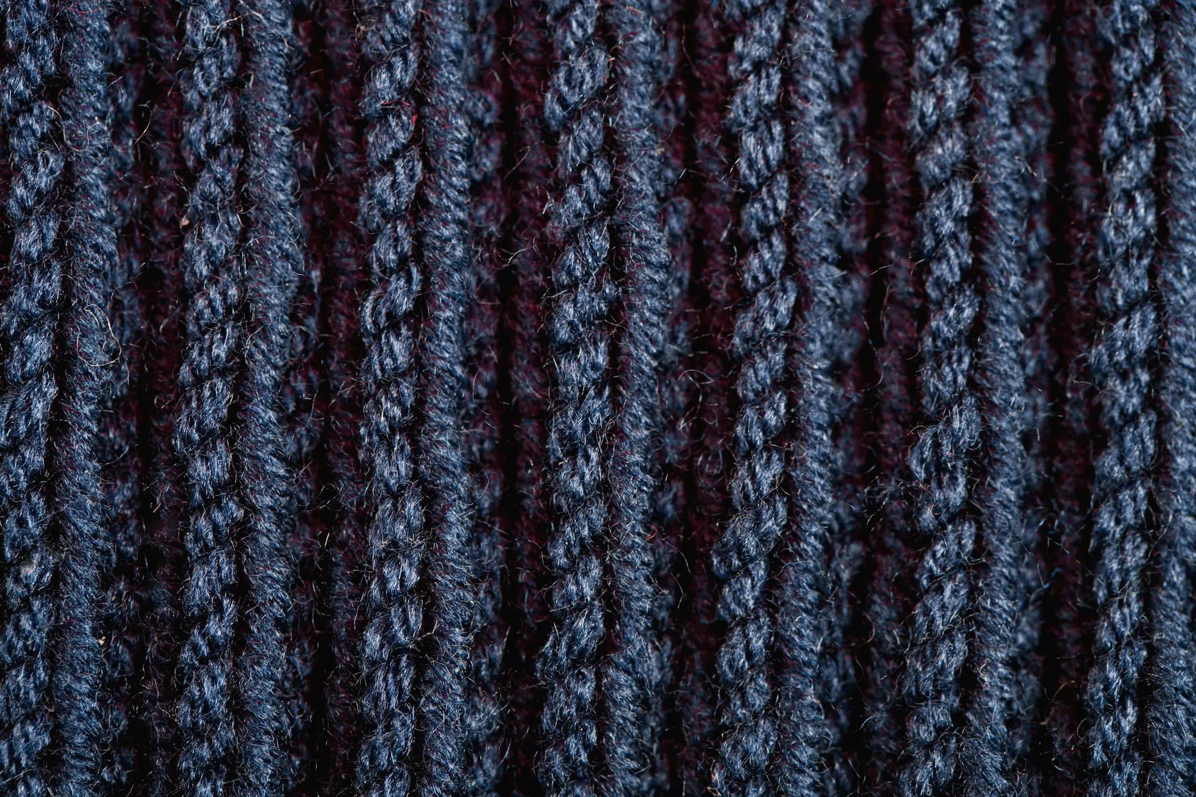 Macro of chunky heathered navy rib knit with burgundy flecks
